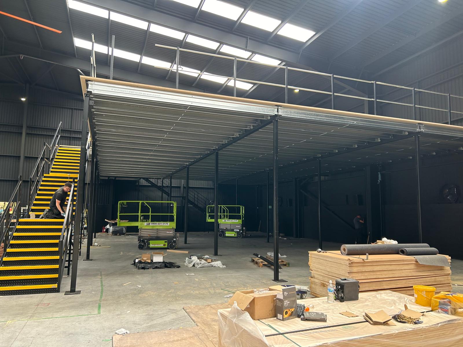 Structural steel mezzanine floor installation with staircase inside industrial unit